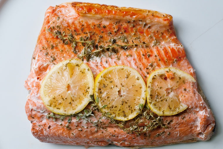 Close up of cooked salmon fillet with herbs and lemon slices on top