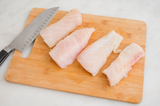 Four Grouper fillet pieces with knife on top of cutting board thumbnail