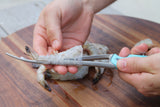 Hands using a Shrimp deveiner that is cleaning headless shrimp thumbnail