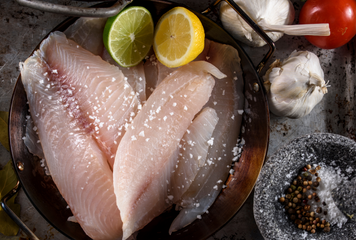 raw tilapia fillet with a lemon and lime also with seasoning   