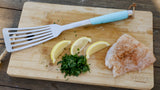 Fish spatula, parsley, lemon slices and fish fillet laying on wood cutting board thumbnail